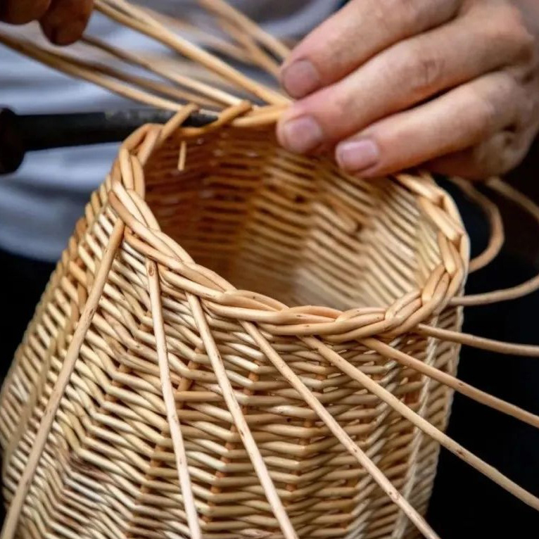 Close-up of artisan hands weaving willow